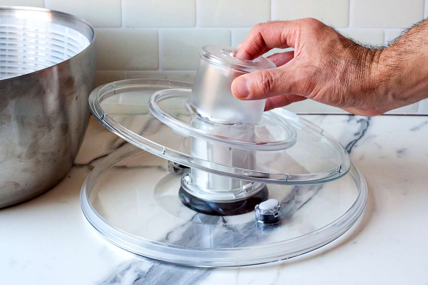 a person taking apart the lid of a salad spinner