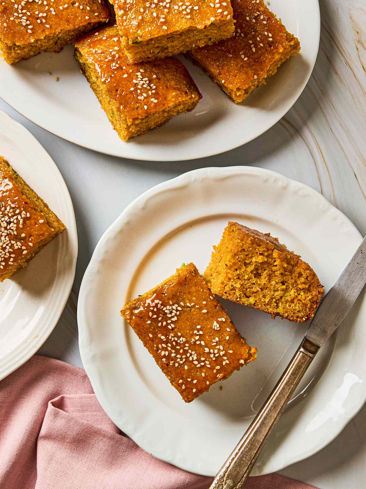 Plates of Gochujang scallion cornbread topped with sesame seeds one plate includes a knife