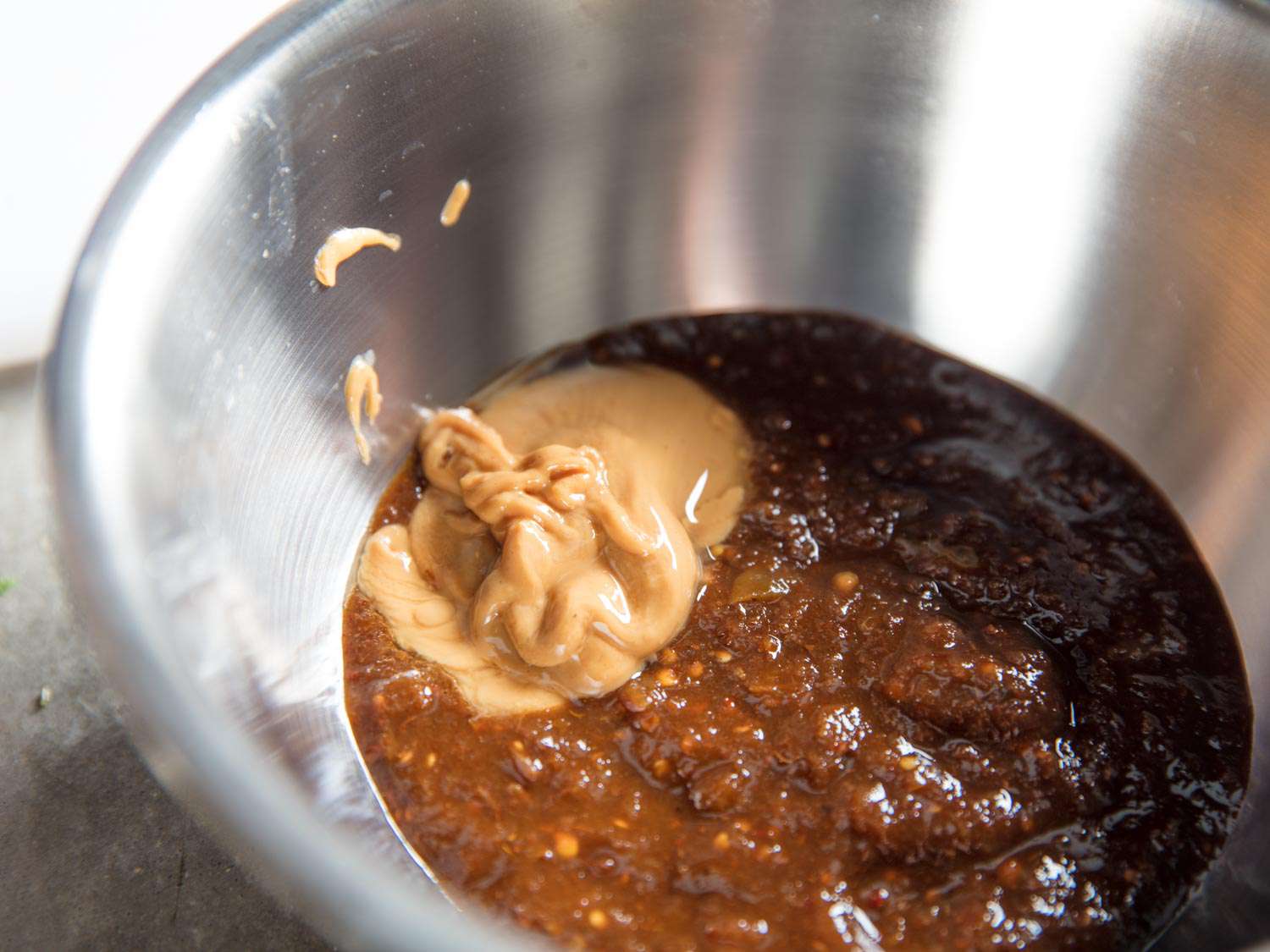 Peanut butter is added to a bowl of dried chile-based salsa.