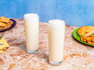 Two Ramos Fizz cocktails, served with brunch food in the background