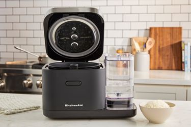 The KitchenAid rice cooker with its lid open on a kitchen countertop.
