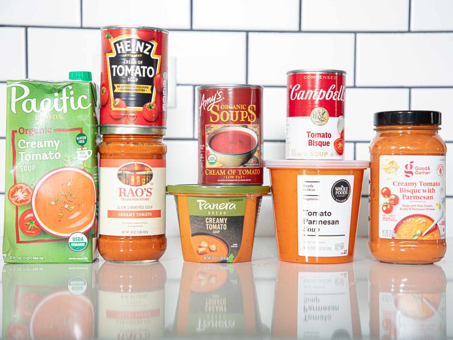 Different brands of tomato soups displayed on a counter including Pacific Heinz Raos Amys Panera and Campbells