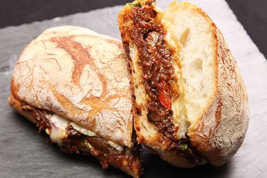 Cross-section view of a braised oxtail and Gruyère cheese sandwich split in half