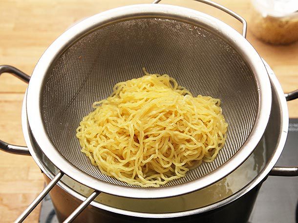 Some just-cooked ramen noodles in a strainer over a pot. 