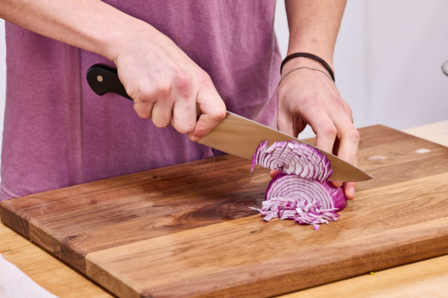 Person slicing a red onion on a wooden cutting board with the Wüsthof Classic 8-Inch Chef's Knife