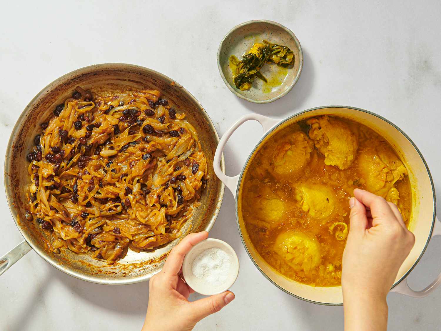 pan of spiced onions next to pot of chicken with salt being added to it, with small dish of discarded cilantro 