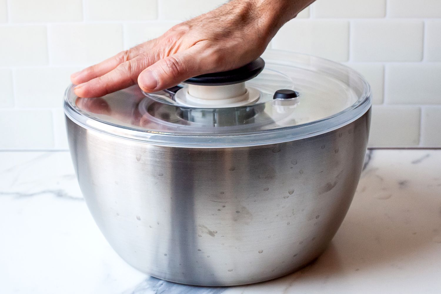 a person pressing the pump on a salad spinner