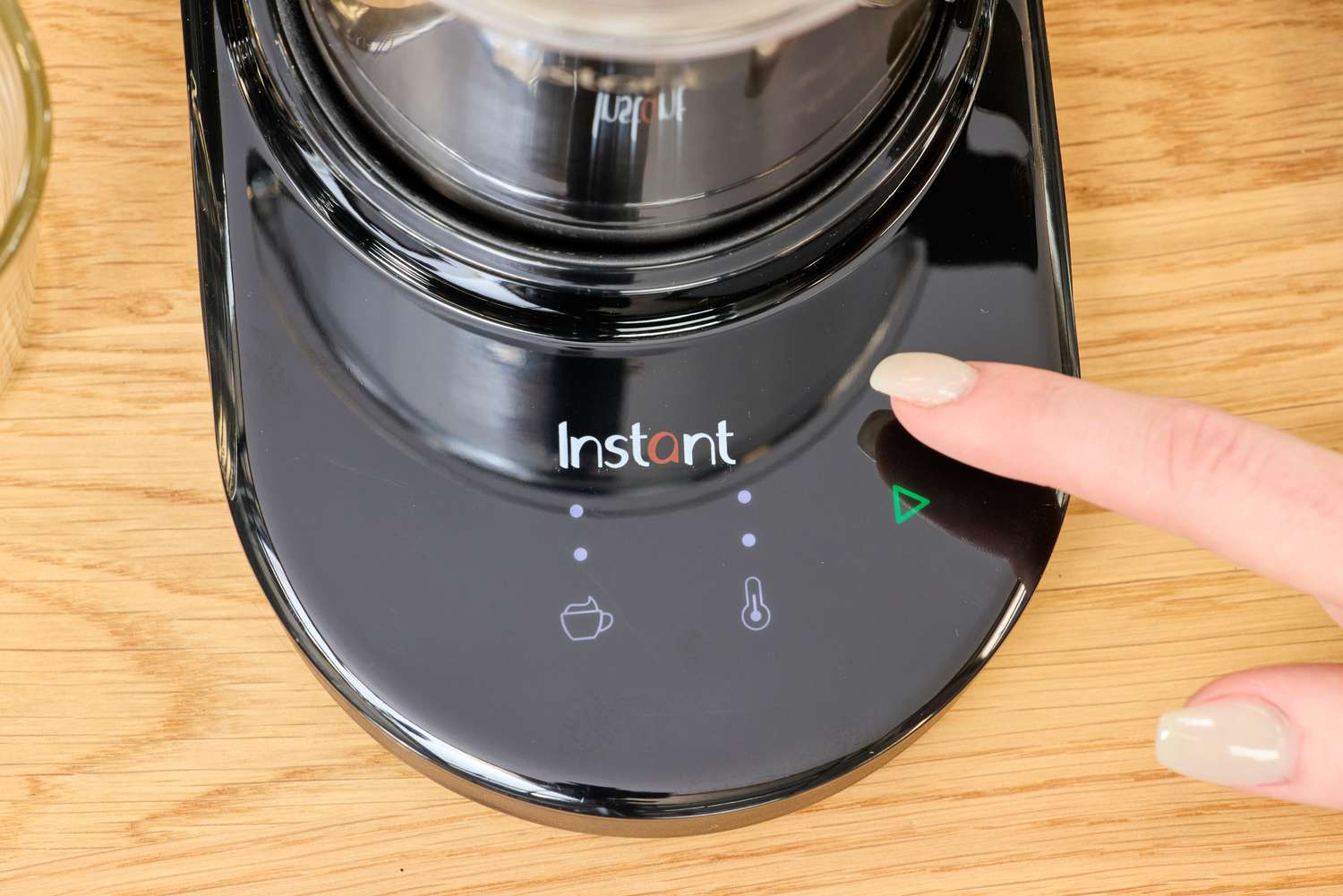 A person tapping the control panel of the Instant milk frother.