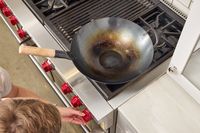An overhead view of the Mammafong Pre-Seasoned Blue Carbon Steel Flat-Bottom Pow Wok on a stove