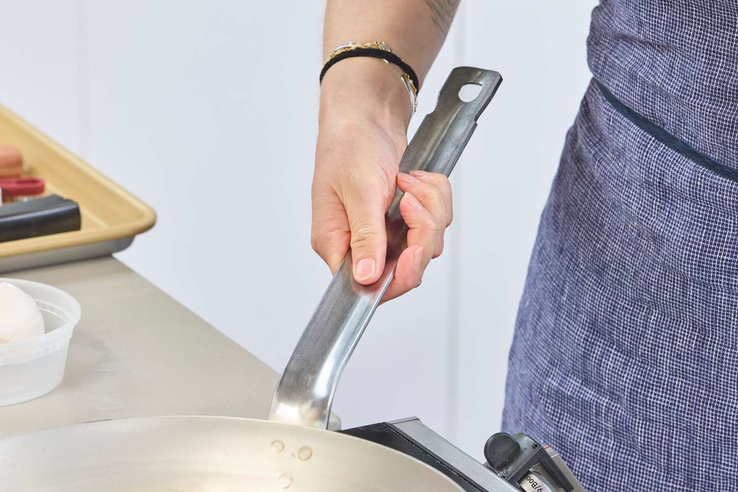 A person holds the handle on the Vollrath 12.5 Inch French Style Carbon Steel Fry Pan