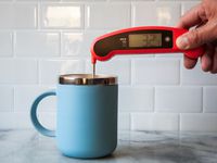 Person using Lavatools Javelin Pro Duo Digital Instant Read Thermometer to check the temperature of a drink in a blue mug
