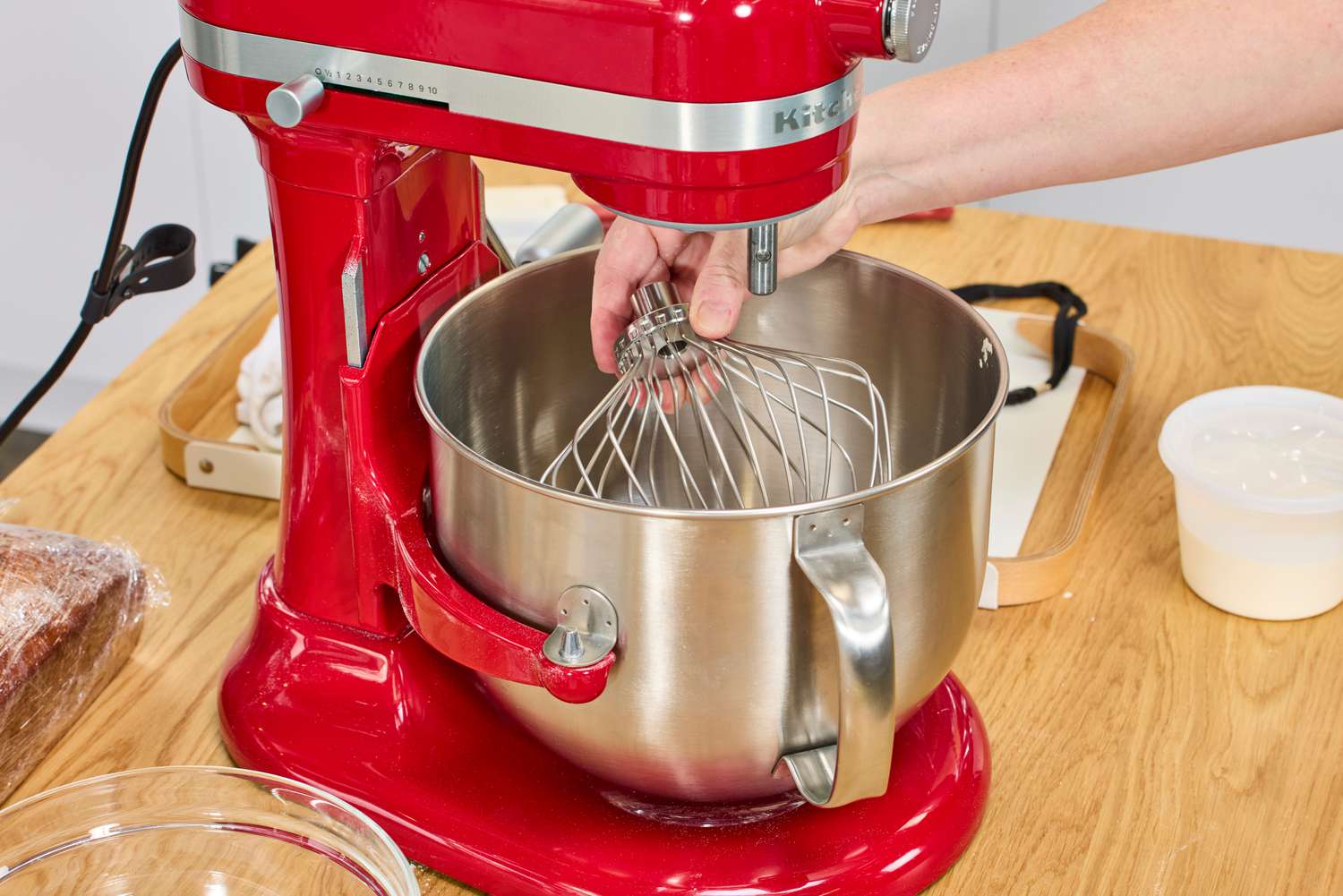 A person removes the whisk attachment on the KitchenAid 7 Quart Bowl Lift Stand Mixer