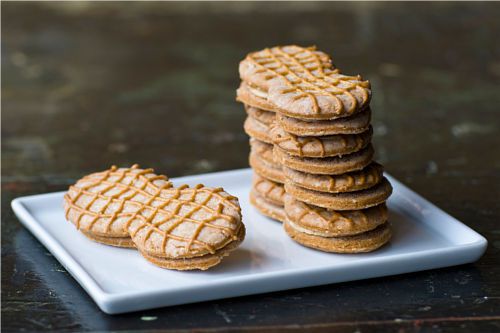 A stack of homemade Nutter Butter cookie sandwiches on a plate.