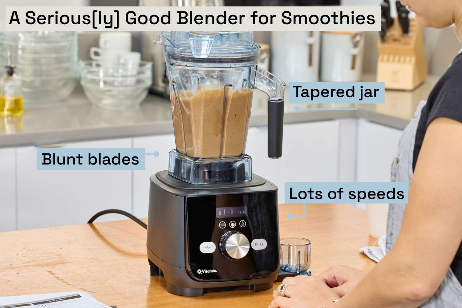 A person looking at a Vitamix blender filled with a smoothie