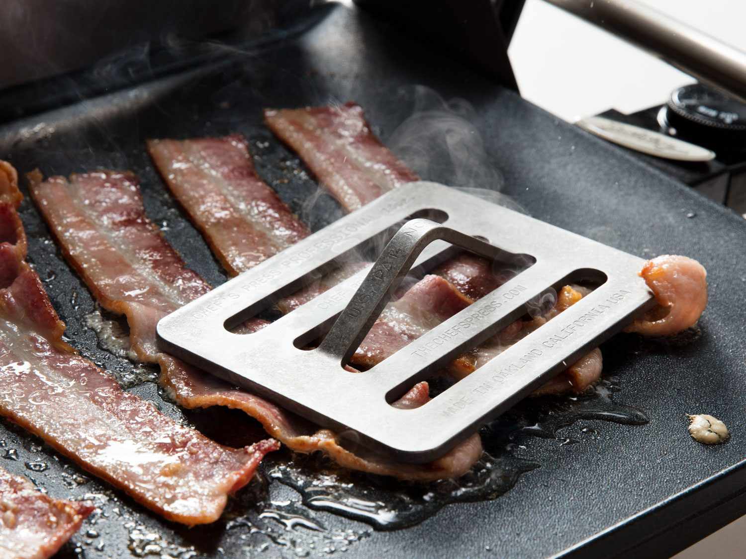 Using a Chef's Press to keep bacon flat on a griddle.