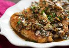 A chicken marsala covered in mushroom and resting on a plate