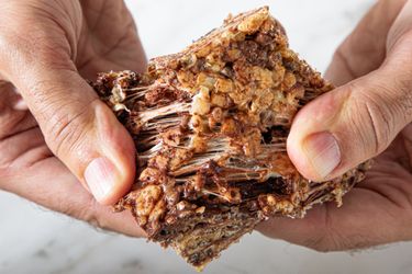 Hands pulling apart a sticky textured crispy rice treat