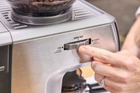 A person turns the grind dial on the Breville The Barista Express Espresso Machine