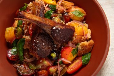 Warm panzanella salad with bread tomatoes and greens in a bowl
