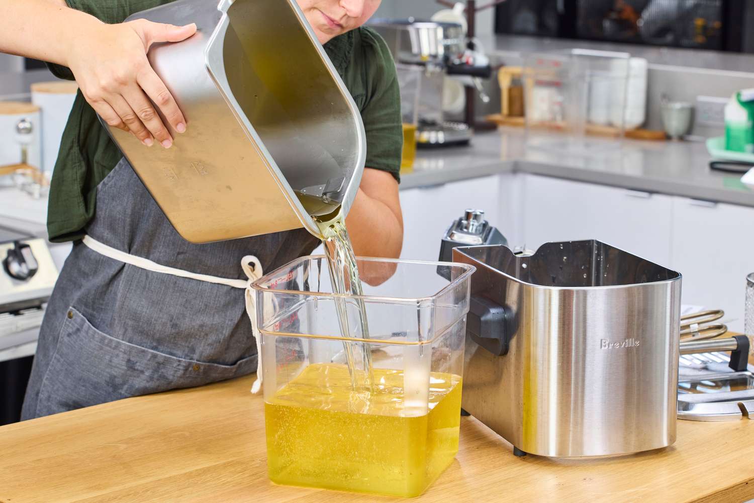 A person pouring oil from the Breville BDF500XL Smart Fryer into a container