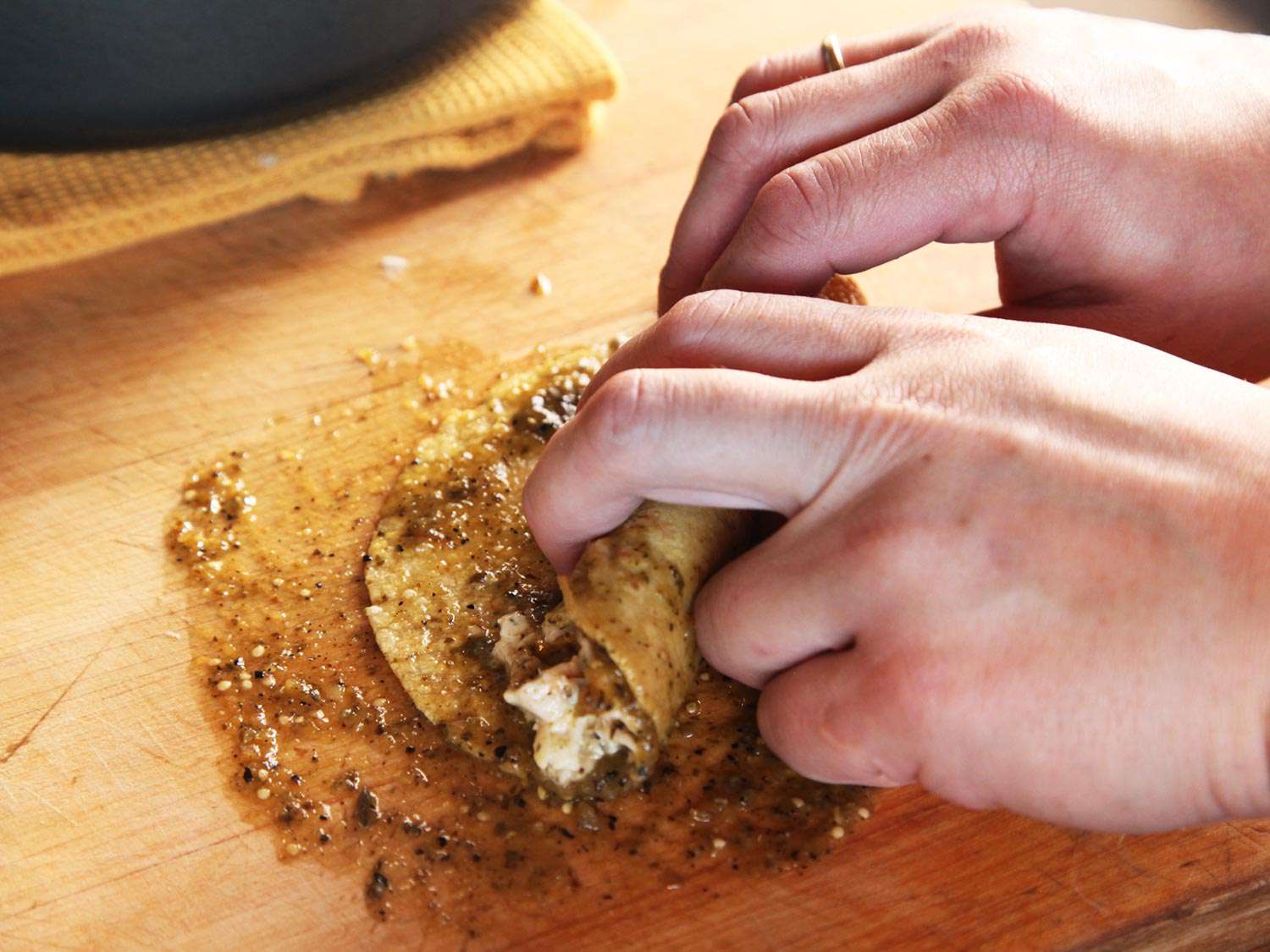 A sauced and filled tortilla is rolled up.