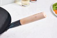 Close-up of the Mammafong Pre-Seasoned Blue Carbon Steel Flat-Bottom Pow Wok's wooden handle