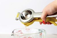 A person pouring citrus juicer from the KitchenAid citrus juicer into a measuring cup.