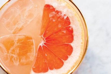 Closeup of grapefruit pisco cocktail topped with half slice of pink grapefruit and coarse salt