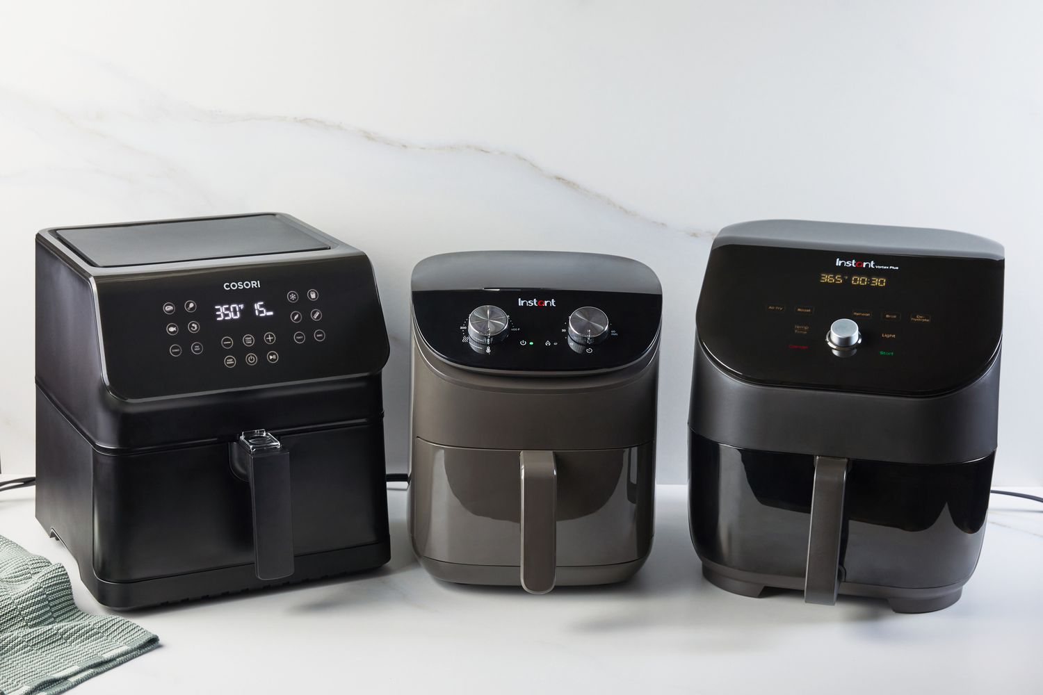 Three air fryers on a kitchen countertop.