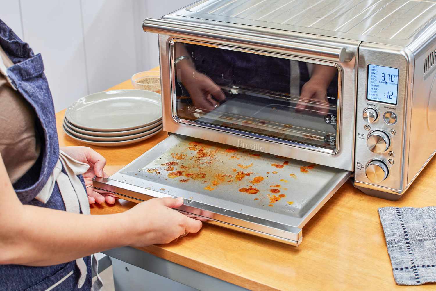 A hand removing a dirty tray from the Breville the Smart Oven Air Fryer