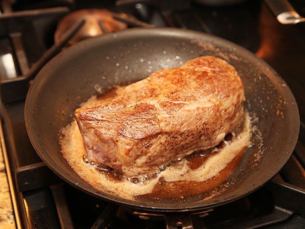 Searing sous vide double cut pork chop in a pan. The chop looks golden brown. 