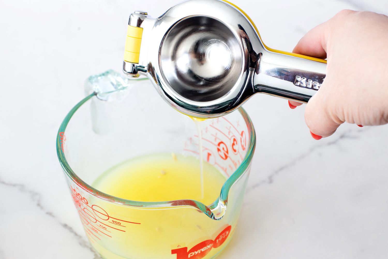 Pouring lemon juice from the KitchenAid citrus juicer into a measuring cup.