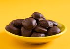 A yellow dish of homemade milk duds set on a yellow background.