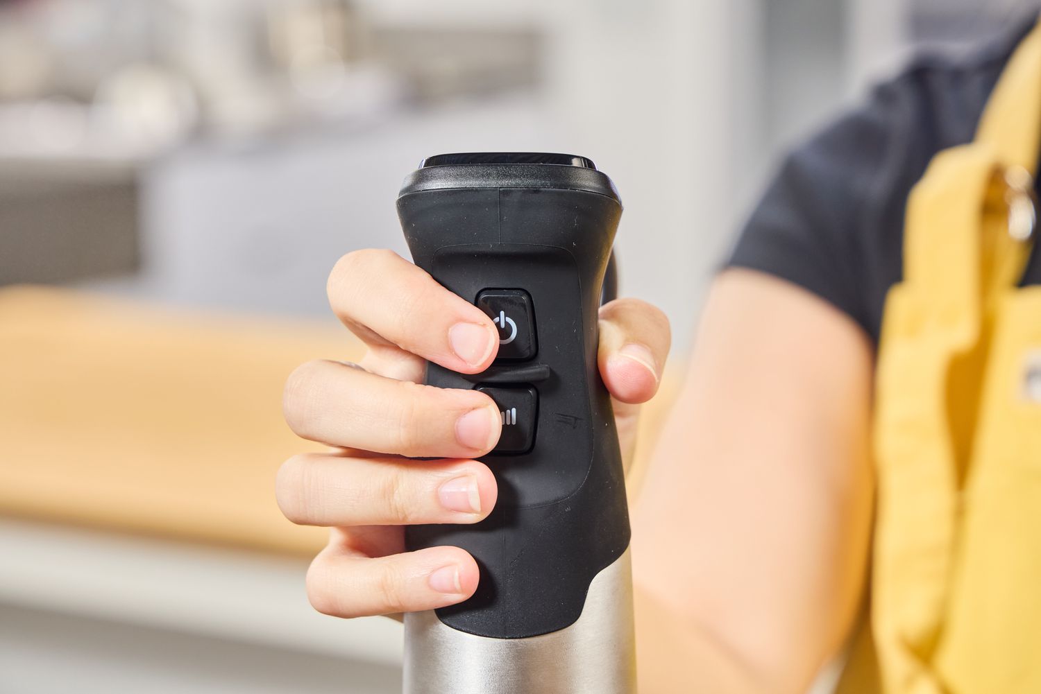 A person presses the power button on the Vitamix Immersion Blender