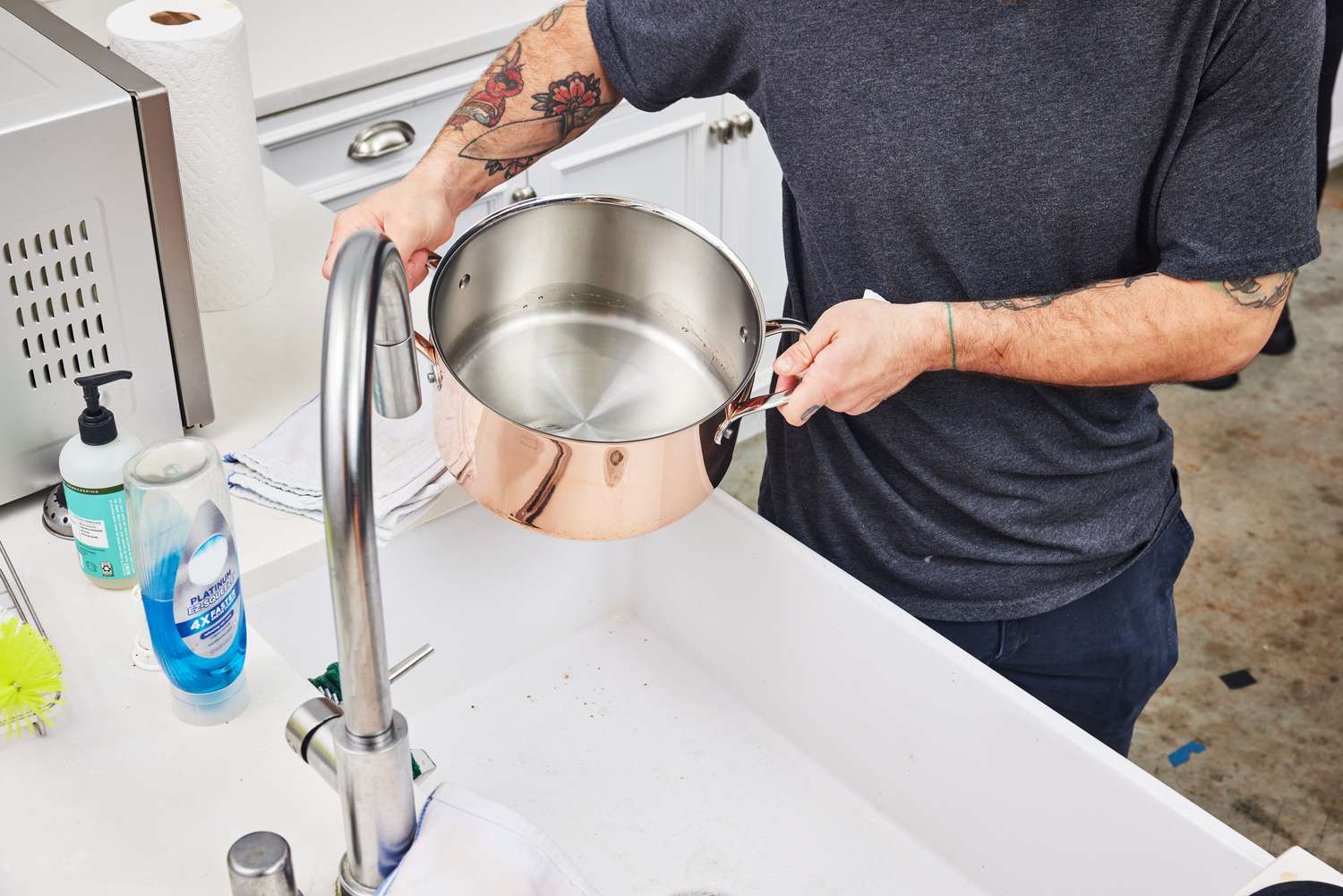 Hands holding Williams Sonoma Thermo-Clad Copper 10-Piece Cookware Set pot near sink