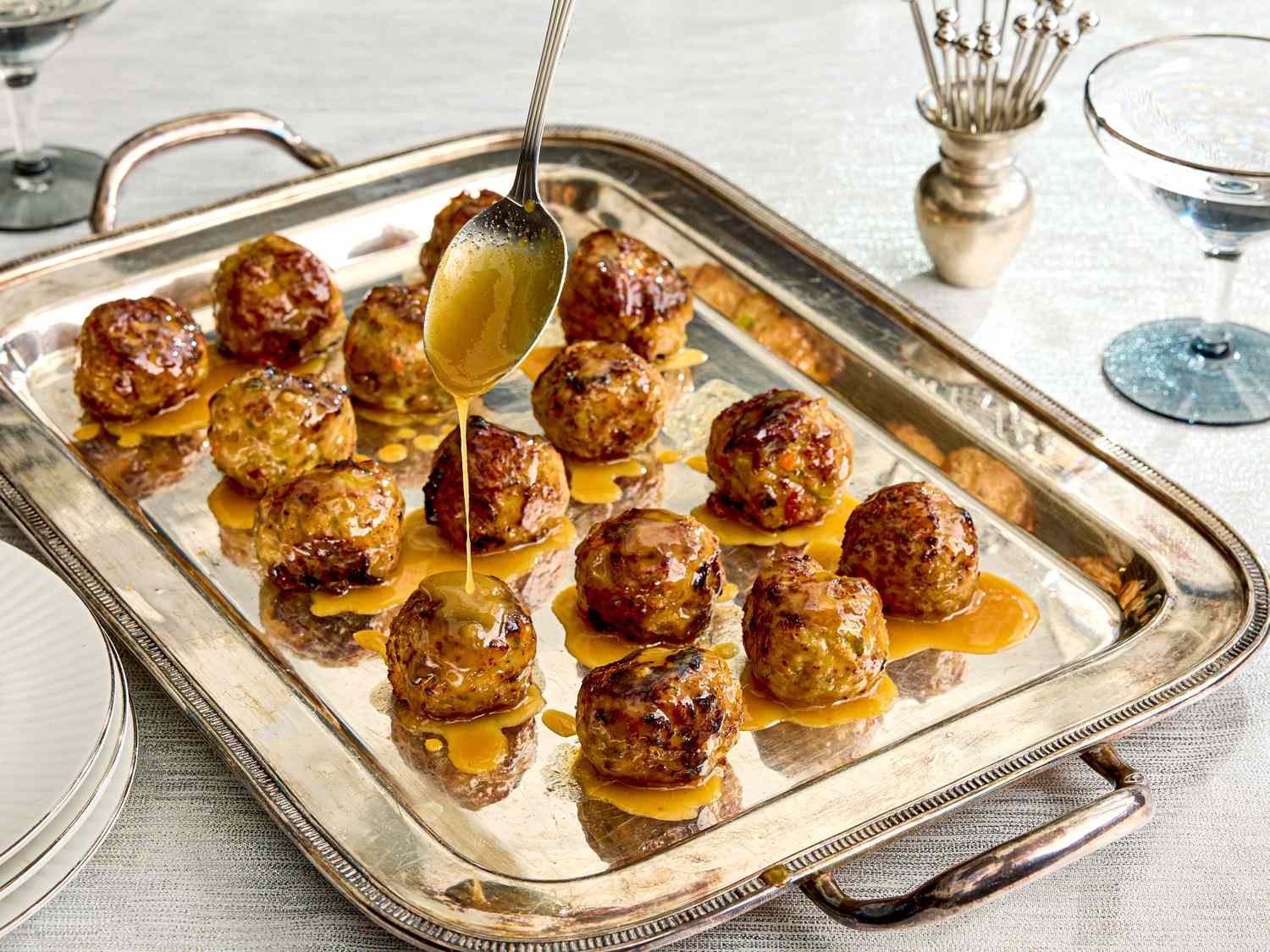 Turkey meatballs on a serving tray being drizzled with a maple mustard glaze