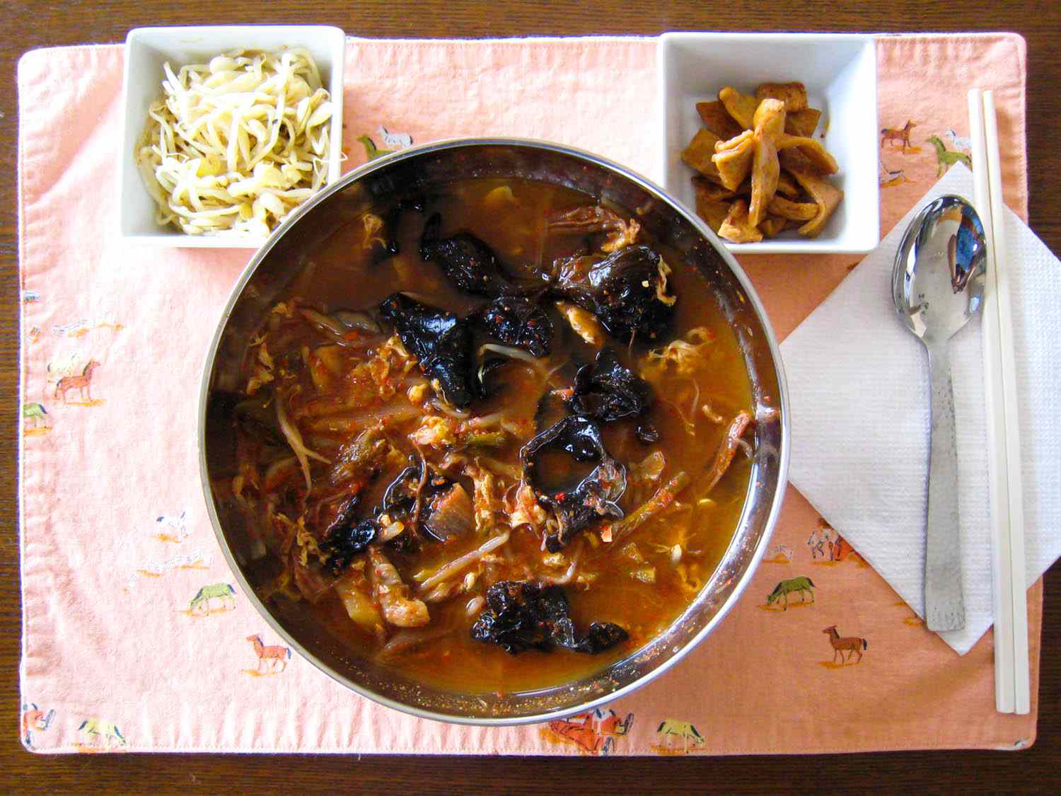 a metal pot of yukgaejang flanked by garnishes