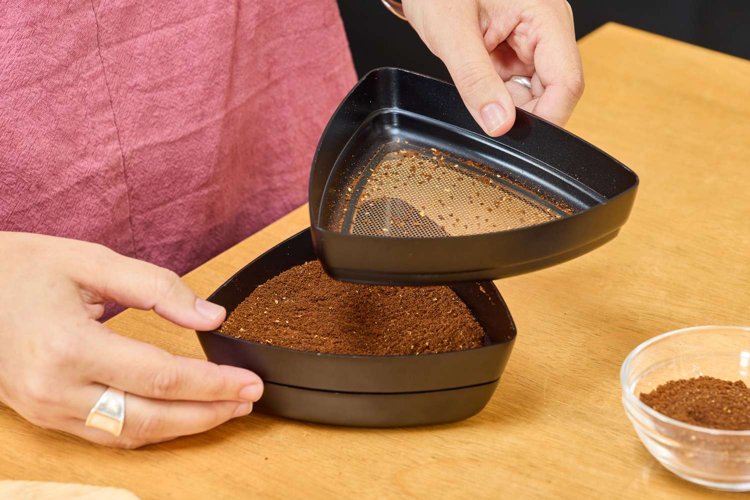 A person sifts coffee beans ground using the OXO Brew Conical Burr Coffee Grinder