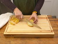 a person cutting a lemon on the made in cutting board