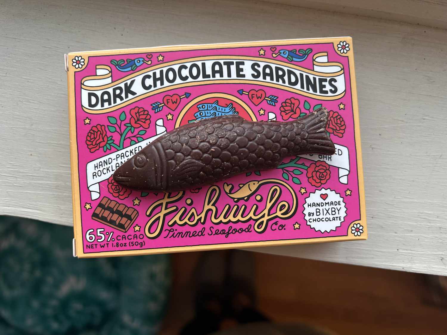 A chocolate-shaped sardine sitting on a pink box