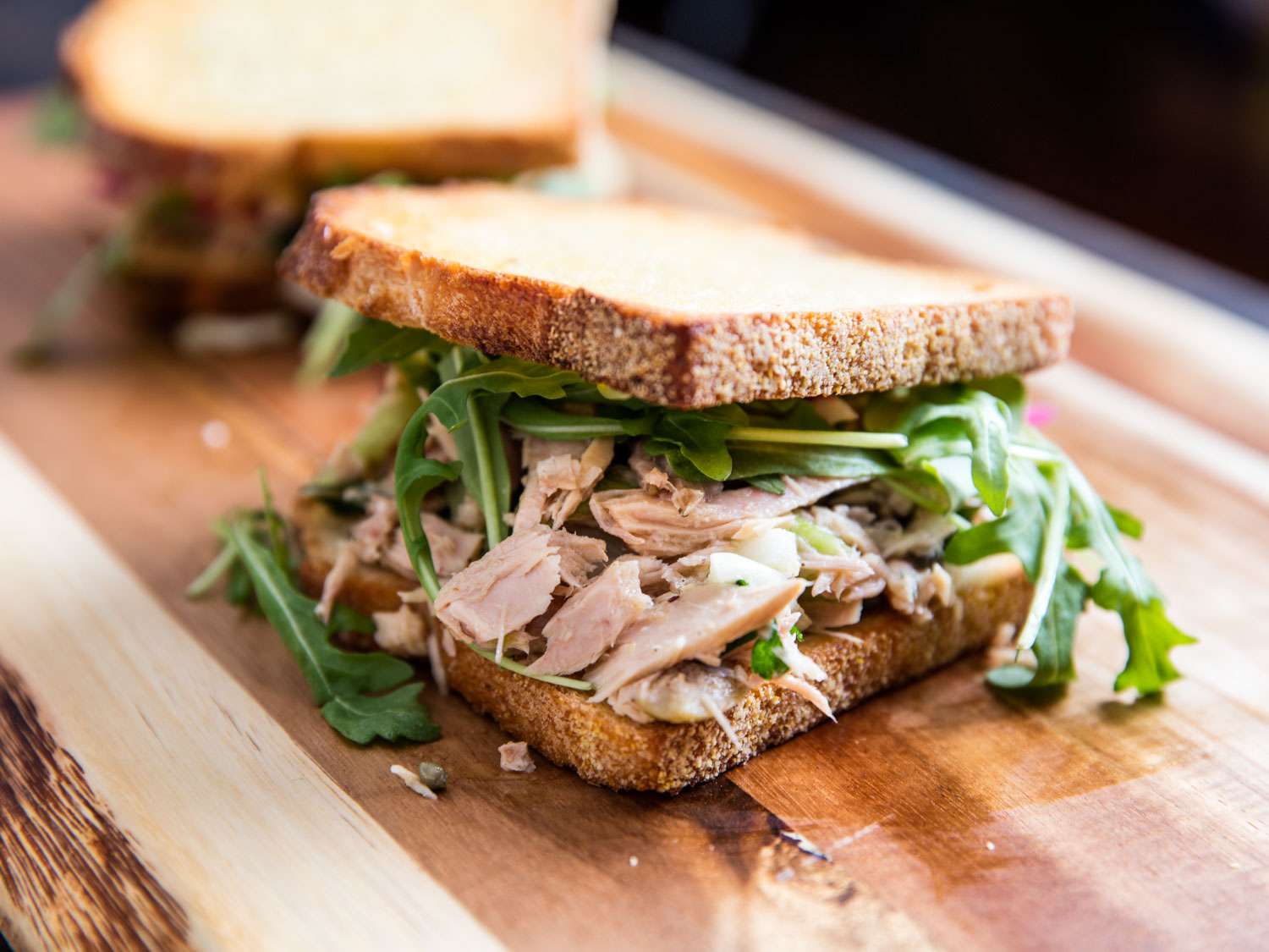 The finished tuna salad sandwich, piled with arugula.