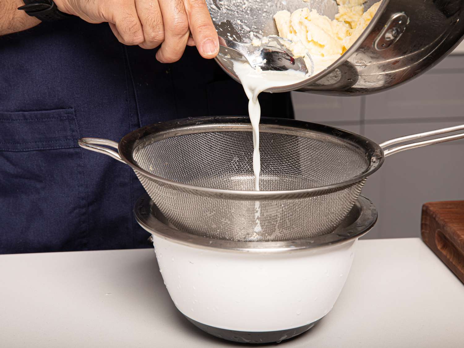 Side view of straining buttermilk from butter into a bowl