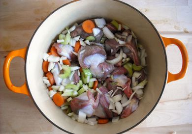 Turkey gizzards in a Dutch oven with chopped vegetables.