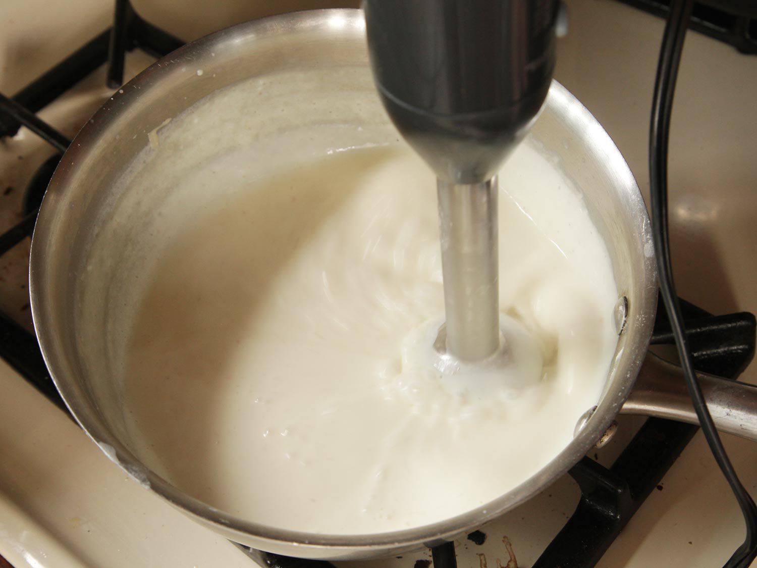 Smoothing out lumps in white sauce with an immersion blender.