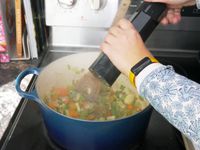a person using the hexill to season mirepoix in a dutch oven