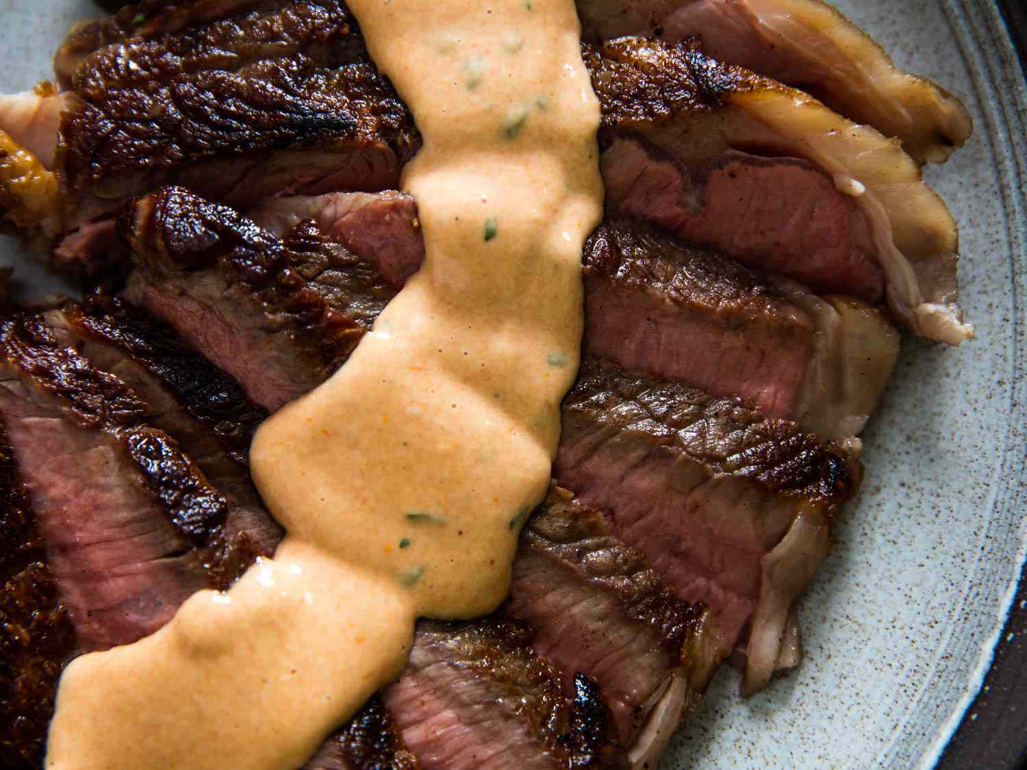 Closeup of a sliced steak topped with a thick ribbon of Choron sauce.