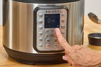 A person presses a button on the Instant Pot Duo Plus 6-Quart 9-in-1 Pressure Cooker