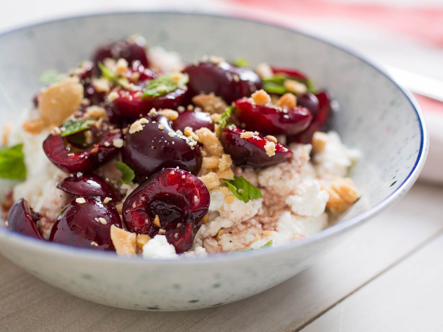 Closeup of sweet-sour cherries with ricotta, almonds, and mint.