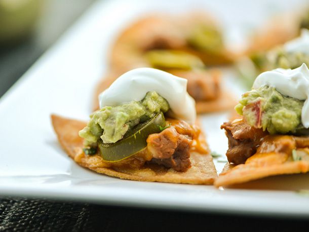 Profile closeup of a Texas nacho with refried beans, guacamole, and sour cream.
