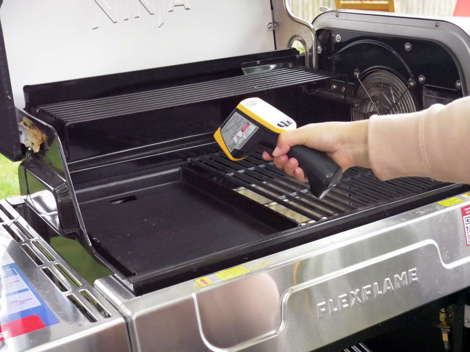 a person using an infrared thermometer to take the temperature of the griddle in the grill